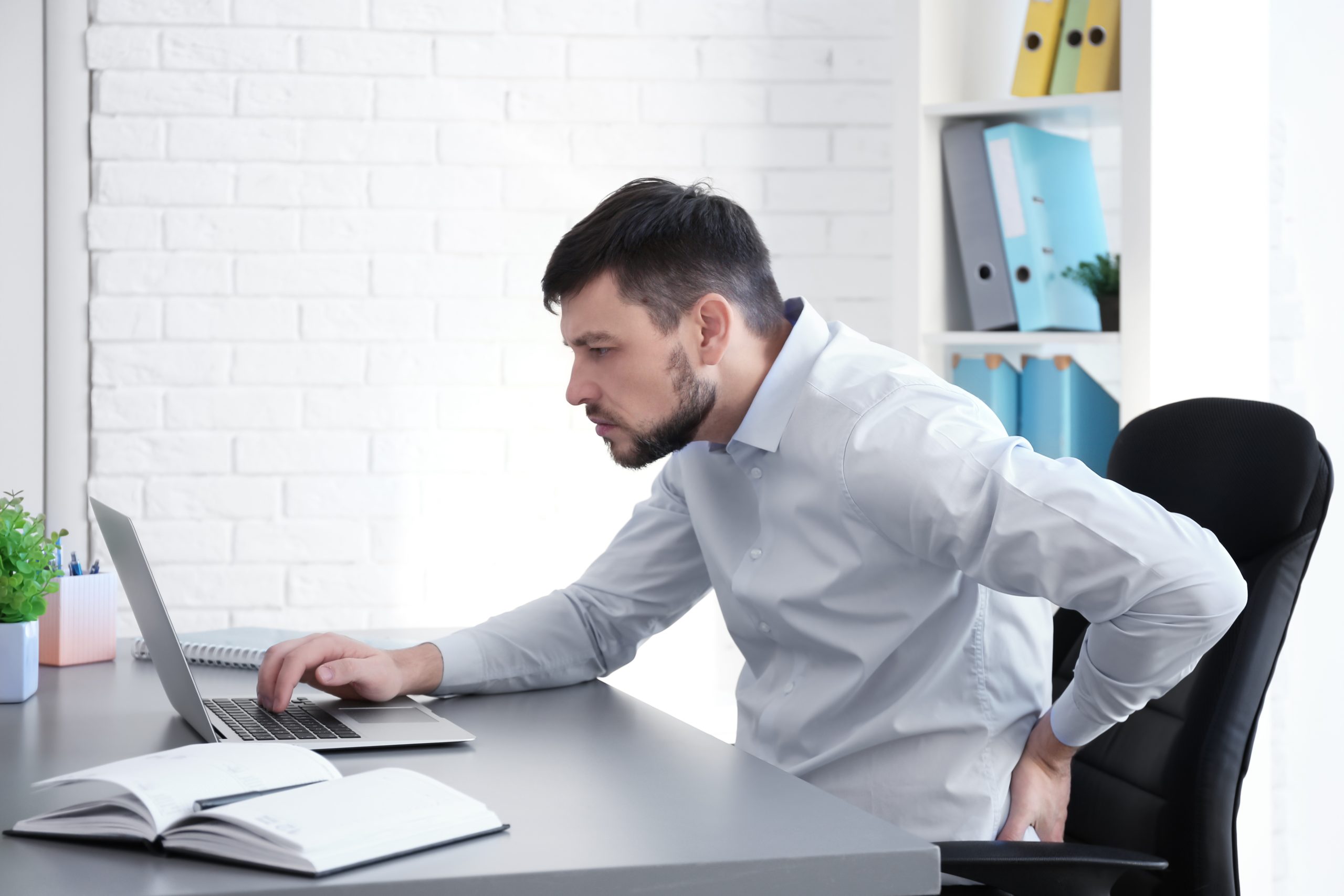 A man hunched over his desk with poor posture