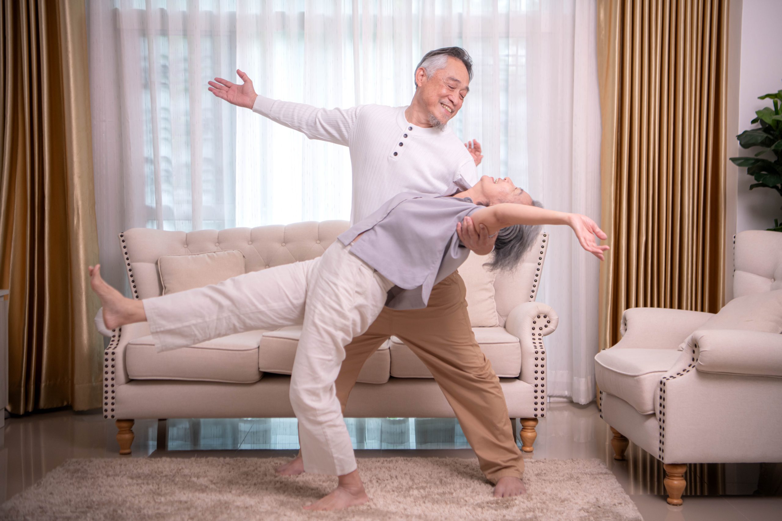 Senior couple practicing dance and balance exercises together at home.