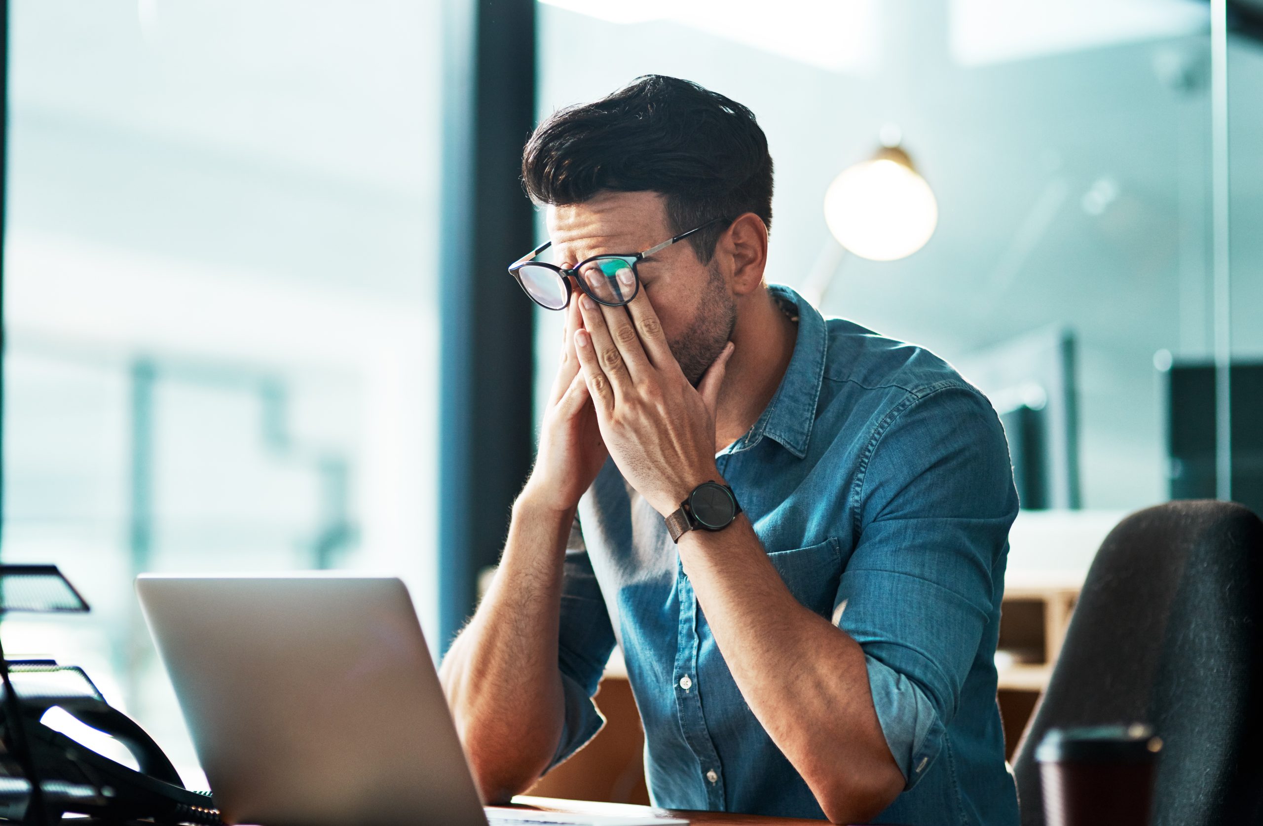 Headache, stress and tired business man at laptop in office for anxiety, debt crisis and eye strain problem.