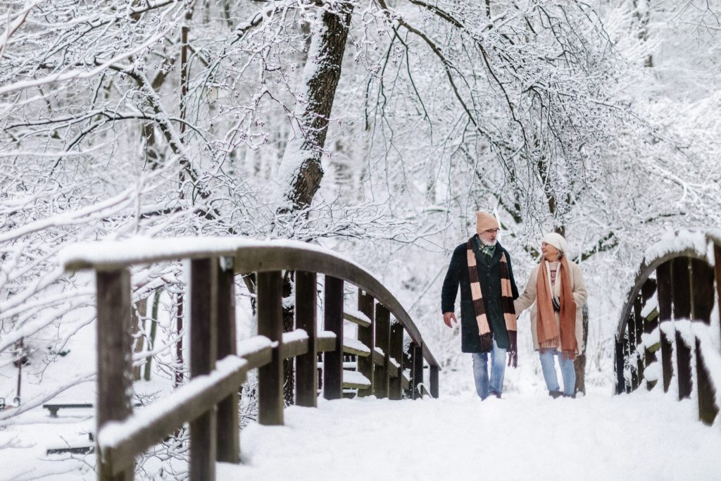 Older couple walking together outdoors on a snowy winter day.